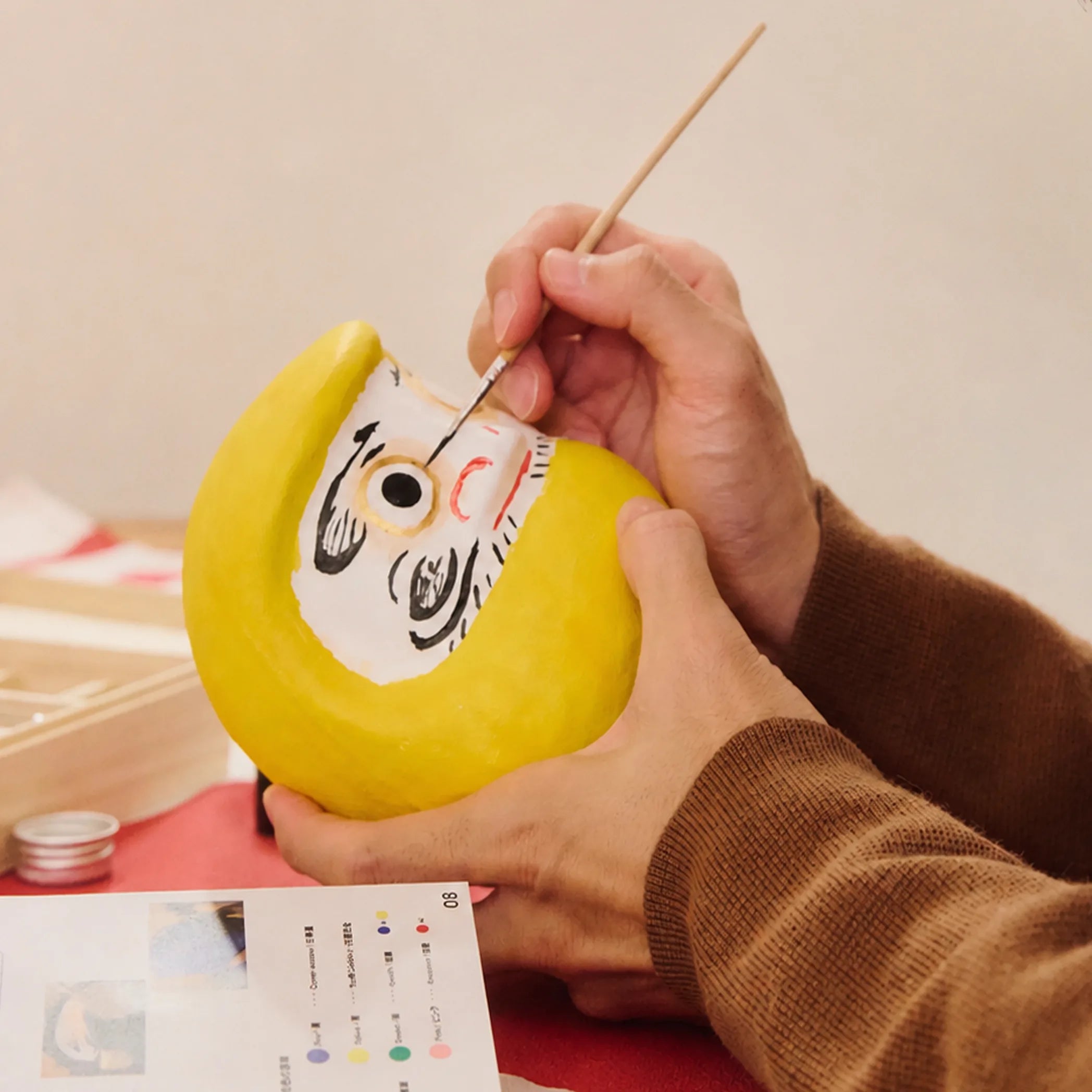 Painting the second eye on a finished yellow daruma