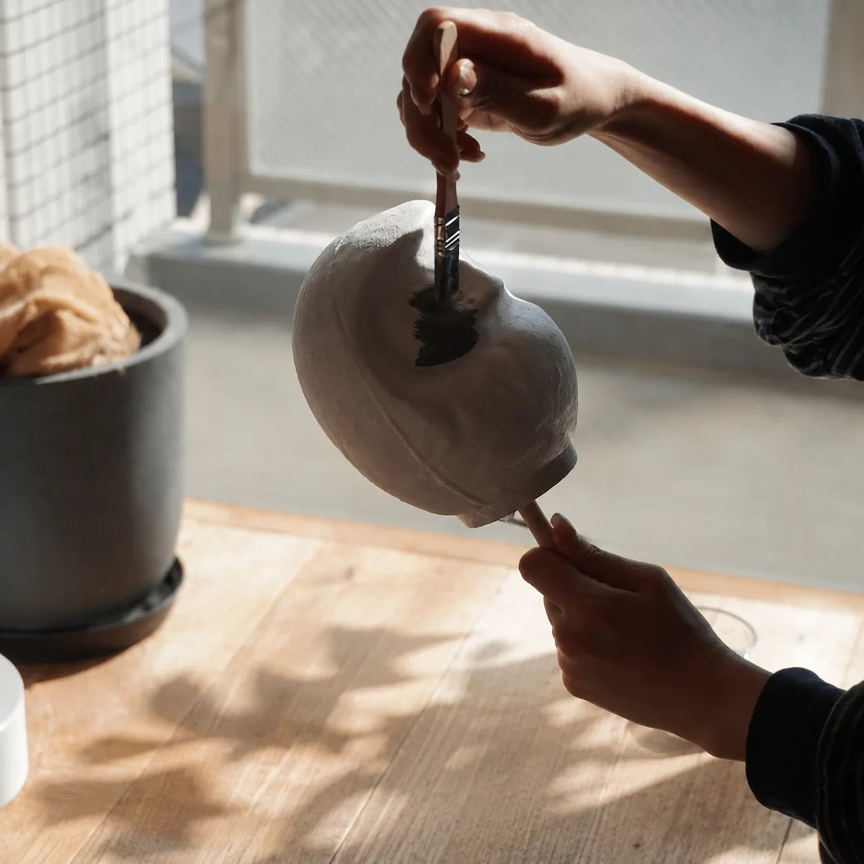 Painting a blank Daruma by a window