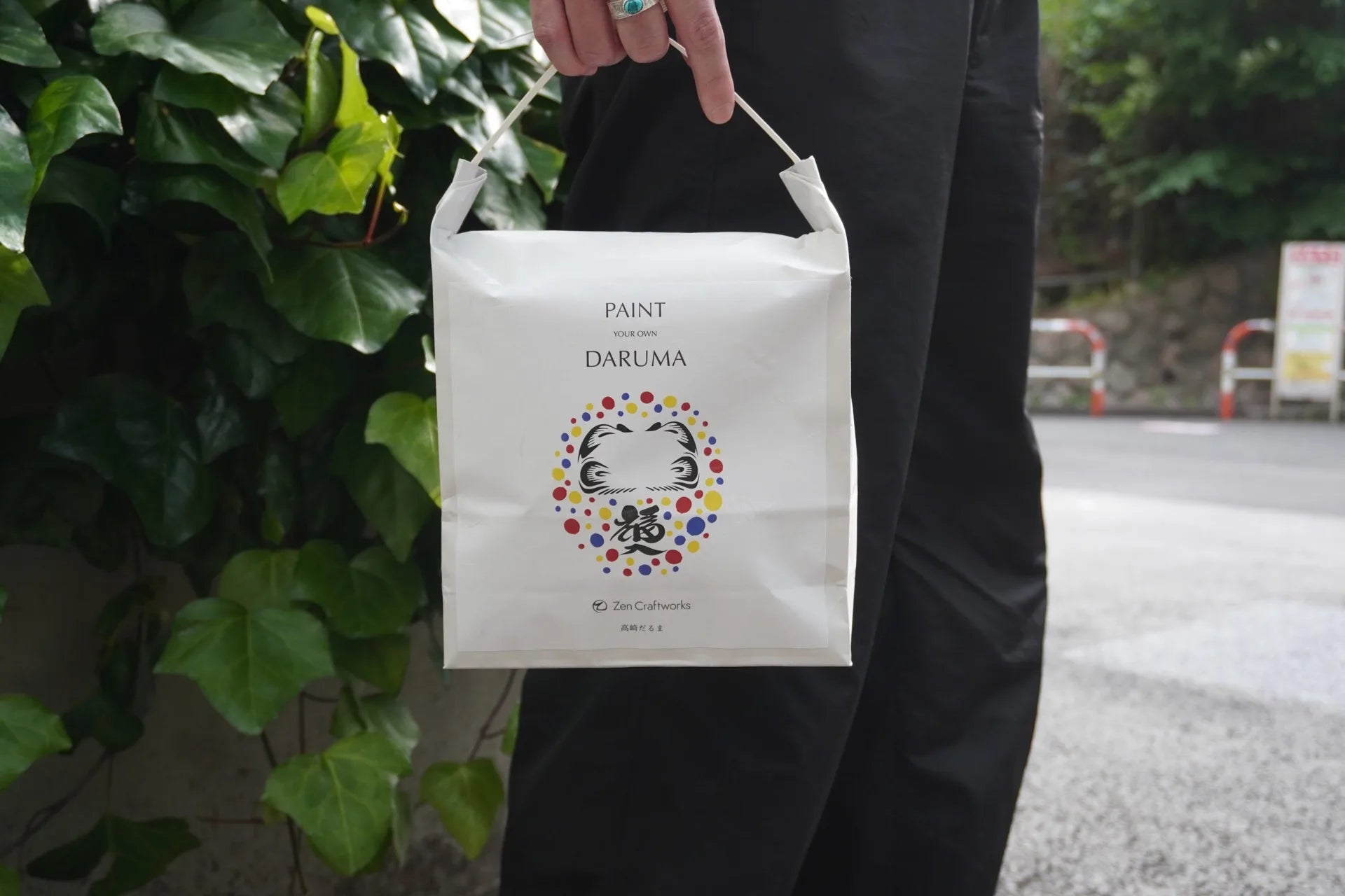 Zen Craftworks Daruma kit paper bag held outdoors