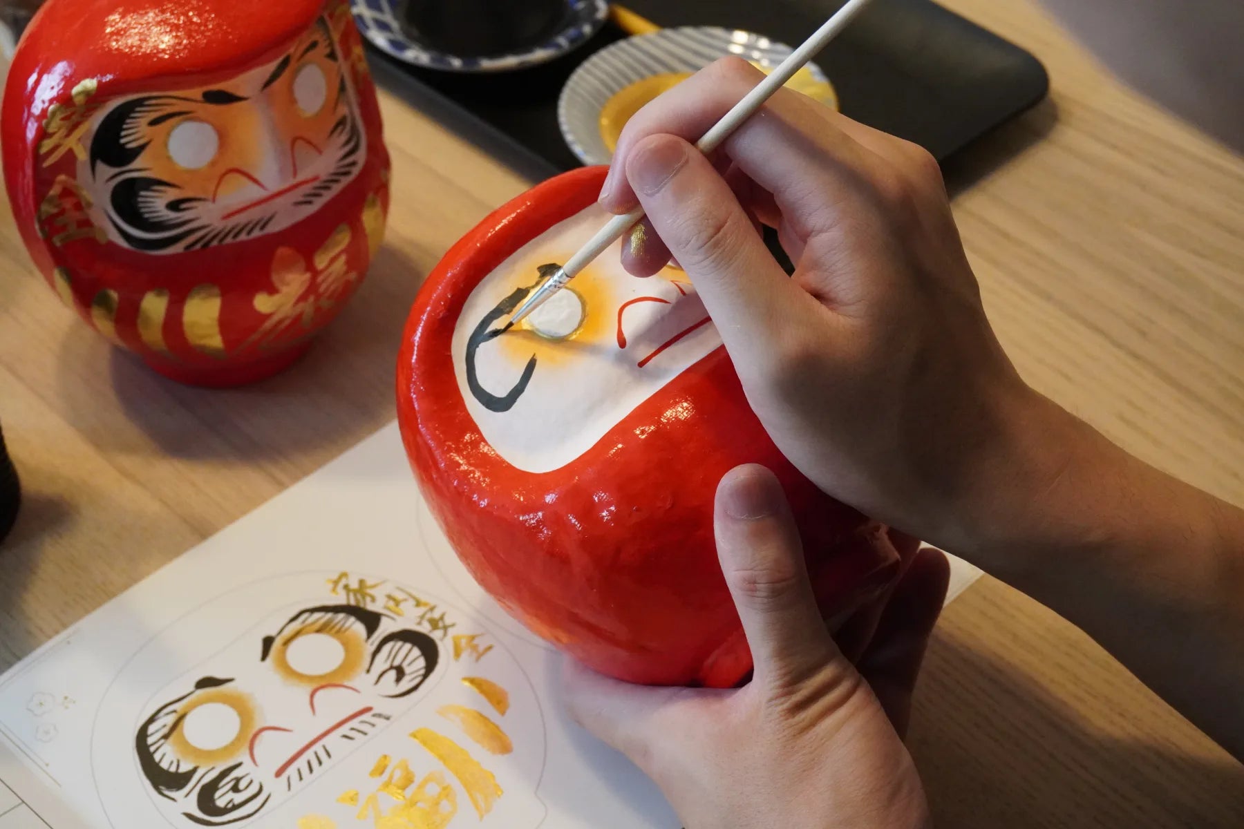 Painting details around the eyes of a Takasaki Daruma