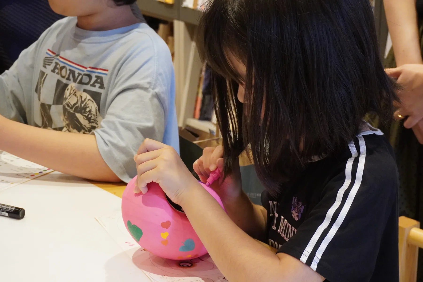 A child painting a pink Takasaki Daruma