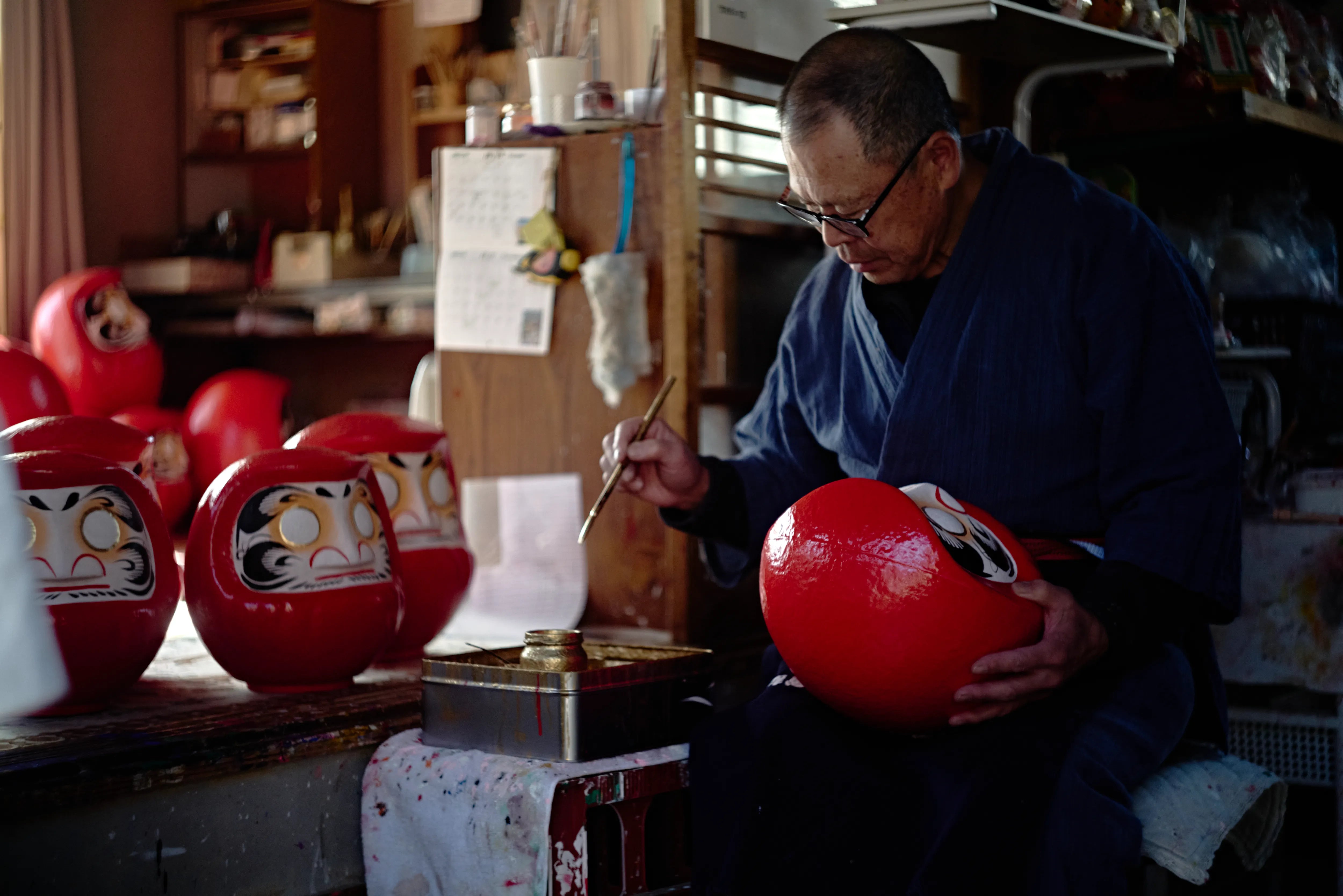 A Takasaki Daruma artisan painting a Daruma