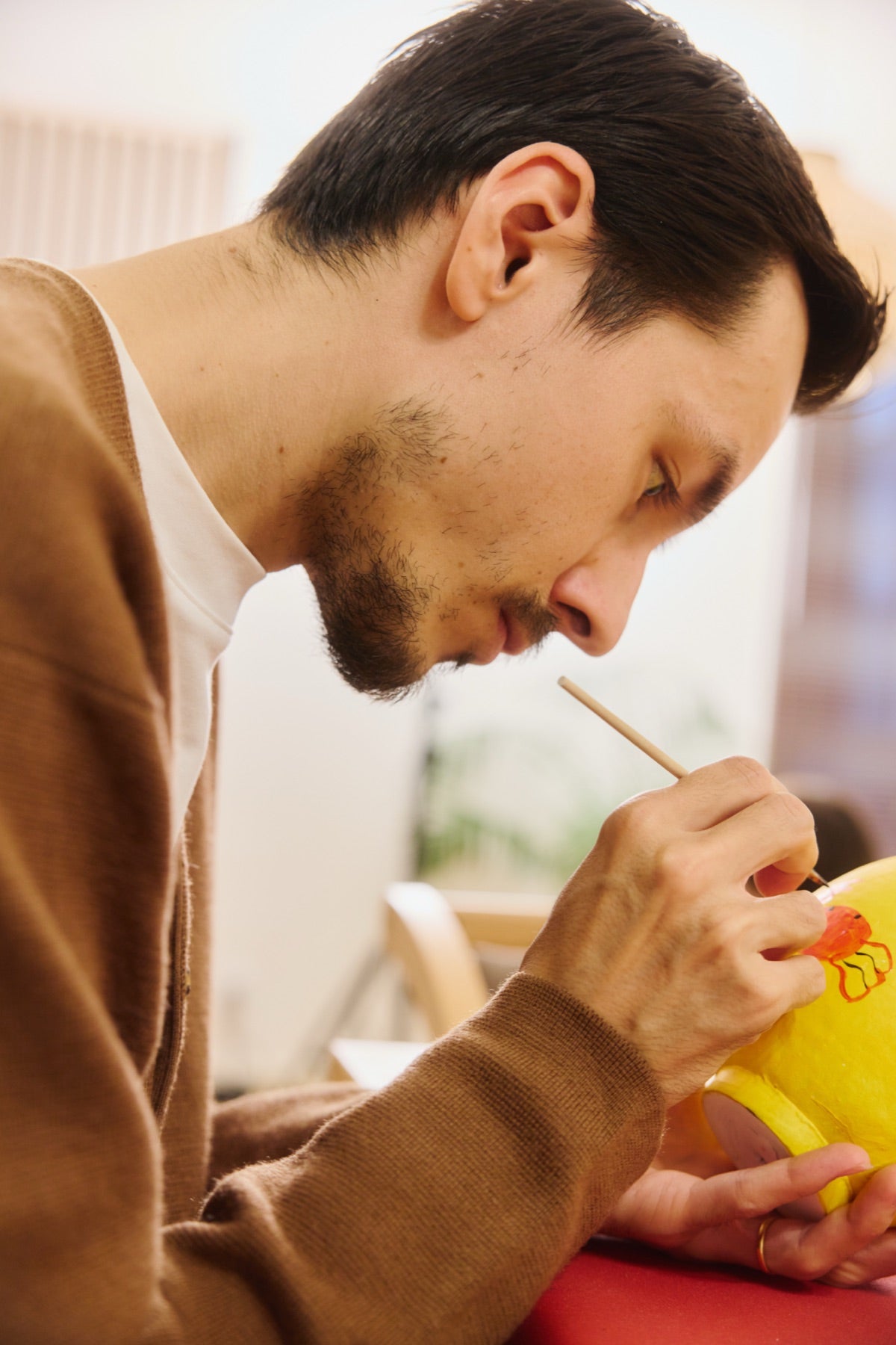 A guest painting a yellow Daruma
